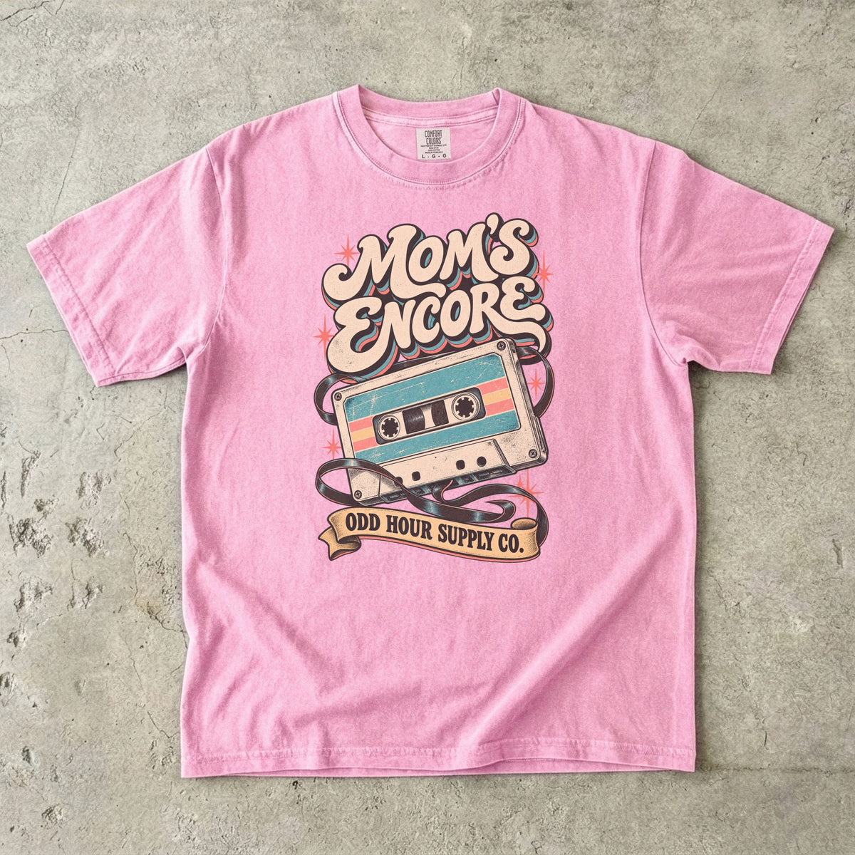 Blossom Comfort Colors 1717 T-shirt with a turquoise and cream cassette, loose tape, coral stars, and Mom’s Encore lettering.
