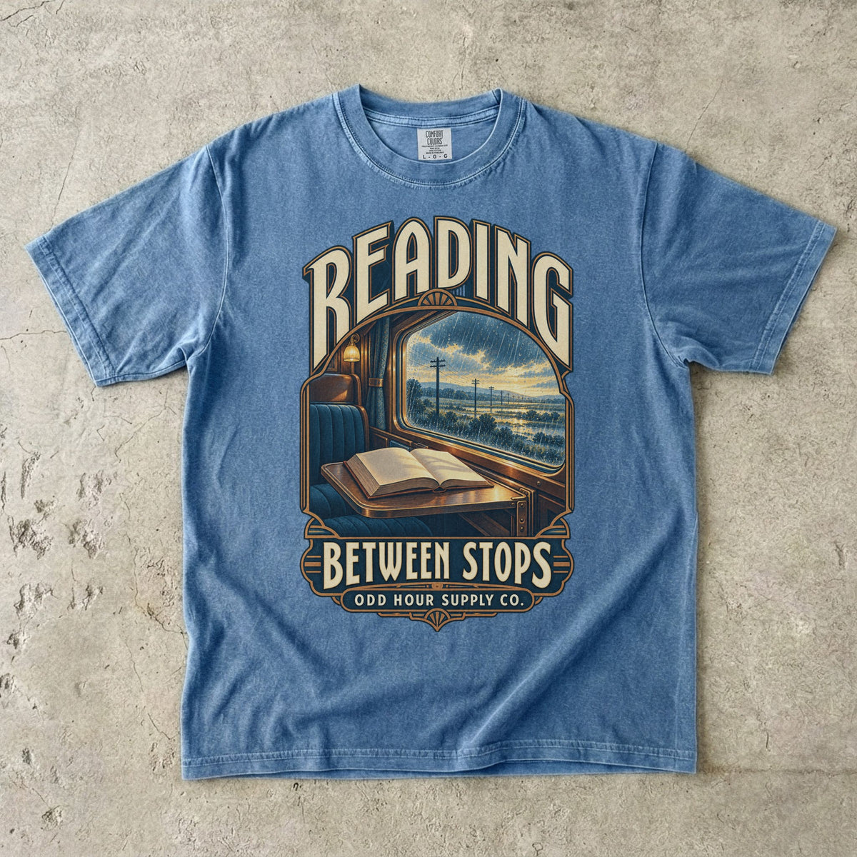 Blue Jean T-shirt with a train window, open book and READING BETWEEN STOPS by Odd Hour Supply Co.