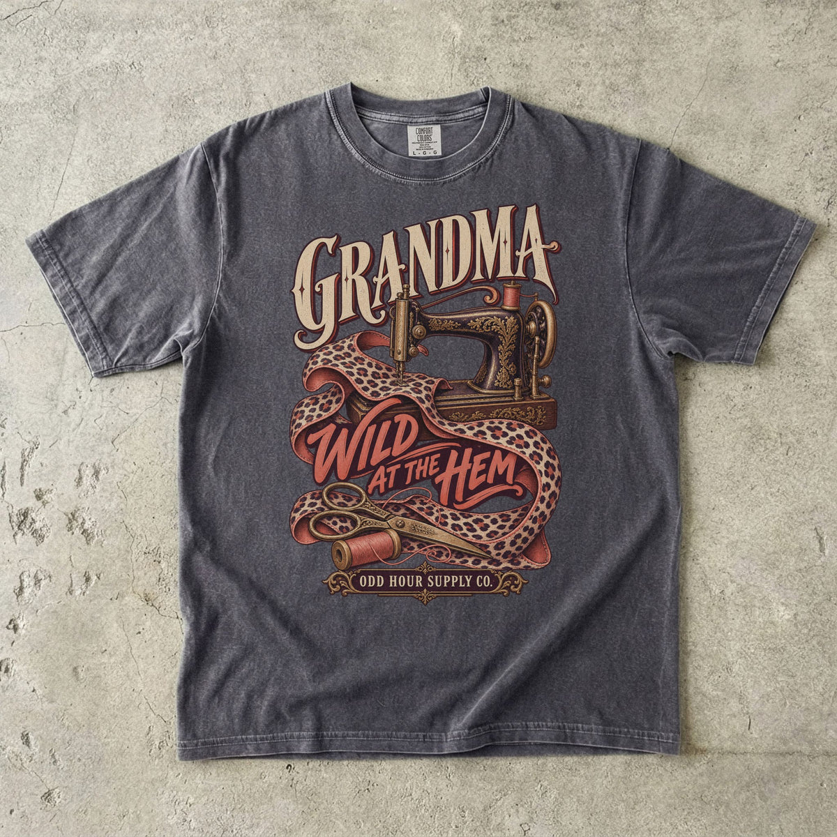 Pepper Comfort Colors 1717 T-shirt with an ornate sewing machine, leopard-print fabric, thread spools, and Grandma Wild at the Hem lettering.