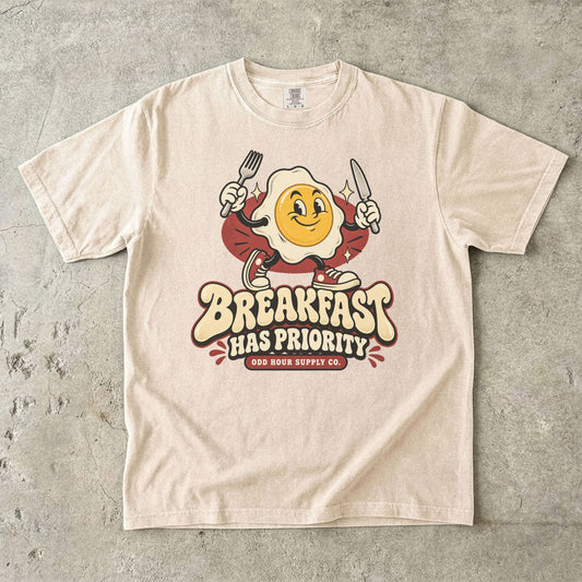 Ivory Comfort Colors 1717 T-shirt with the Breakfast Has Priority graphic, front view