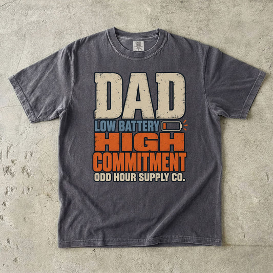 Pepper Comfort Colors 1717 T-shirt with large Dad Low Battery High Commitment lettering in cream, blue, and orange and a nearly empty battery symbol.