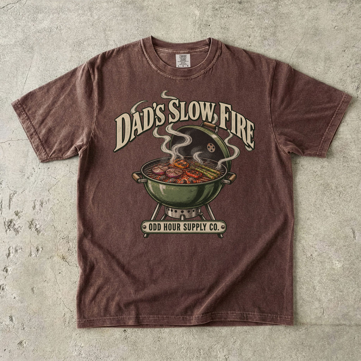 Espresso Comfort Colors 1717 T-shirt with a green kettle grill, vegetables on the grate, curling smoke, and Dad’s Slow Fire lettering.