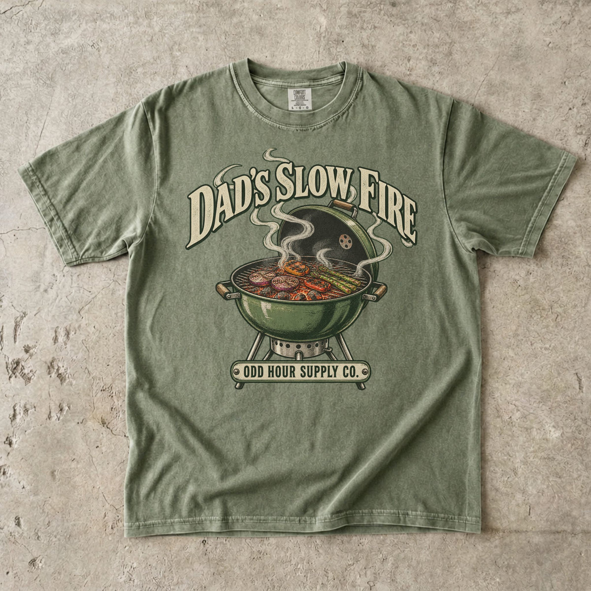 Hemp Comfort Colors 1717 T-shirt with a green kettle grill, vegetables on the grate, curling smoke, and Dad’s Slow Fire lettering.