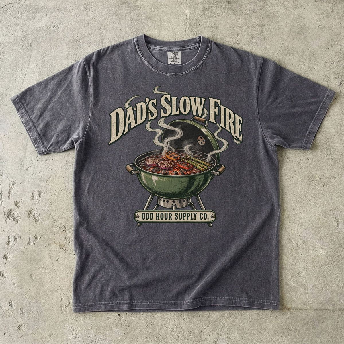 Pepper Comfort Colors 1717 T-shirt with a green kettle grill, vegetables on the grate, curling smoke, and Dad’s Slow Fire lettering.