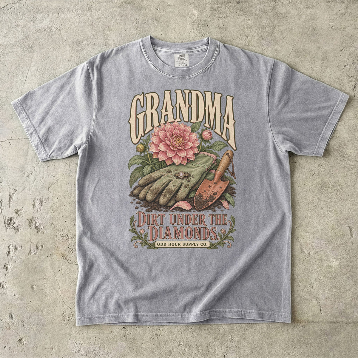 Grey Comfort Colors 1717 T-shirt with gardening gloves, a ring, a pink dahlia, a hand trowel, and Grandma Dirt Under the Diamonds lettering.