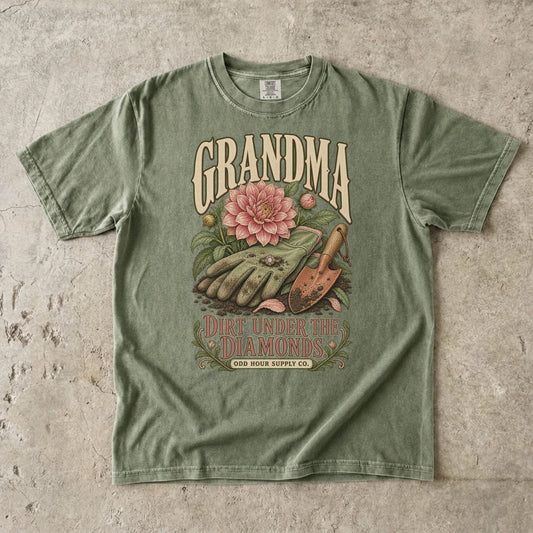 Hemp Comfort Colors 1717 T-shirt with gardening gloves, a ring, a pink dahlia, a hand trowel, and Grandma Dirt Under the Diamonds lettering.