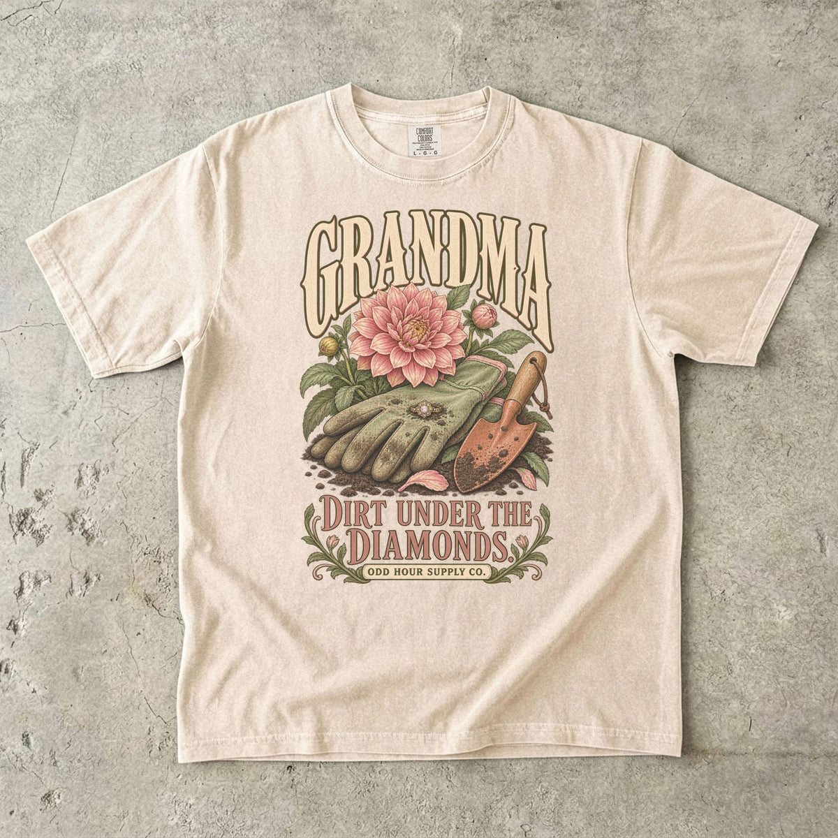 Ivory Comfort Colors 1717 T-shirt with gardening gloves, a ring, a pink dahlia, a hand trowel, and Grandma Dirt Under the Diamonds lettering.