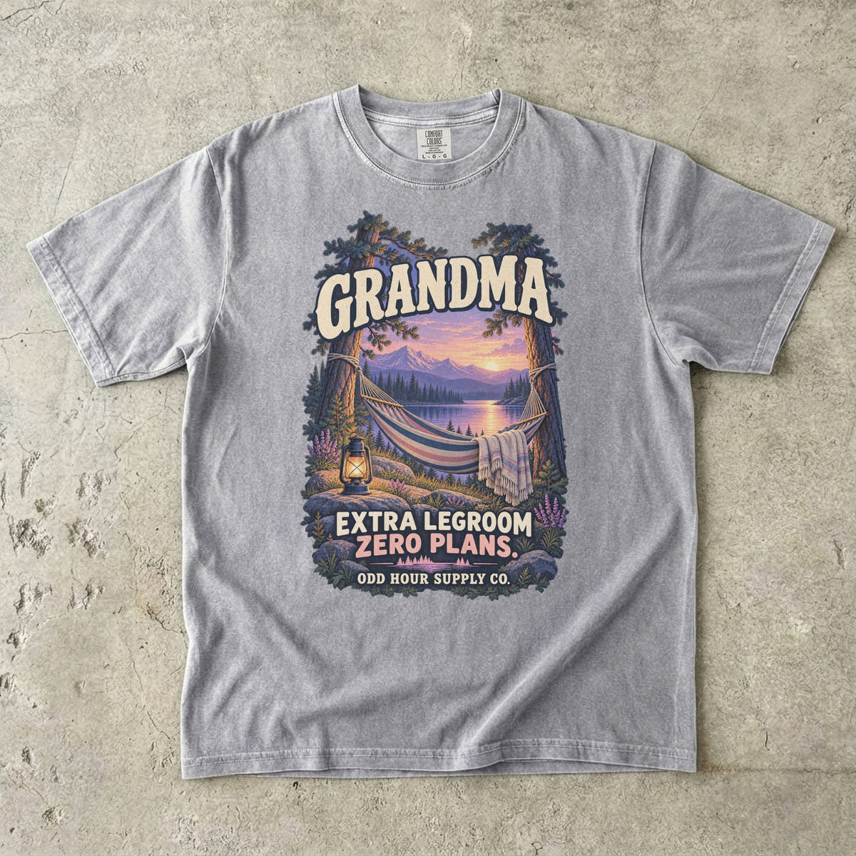 Grey Comfort Colors 1717 T-shirt with a hammock between trees, a lake, mountains, a lantern, and Grandma Extra Legroom Zero Plans lettering.