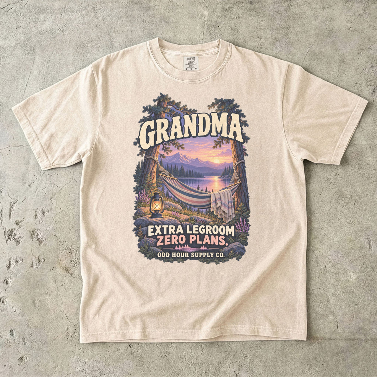 Ivory Comfort Colors 1717 T-shirt with a hammock between trees, a lake, mountains, a lantern, and Grandma Extra Legroom Zero Plans lettering.
