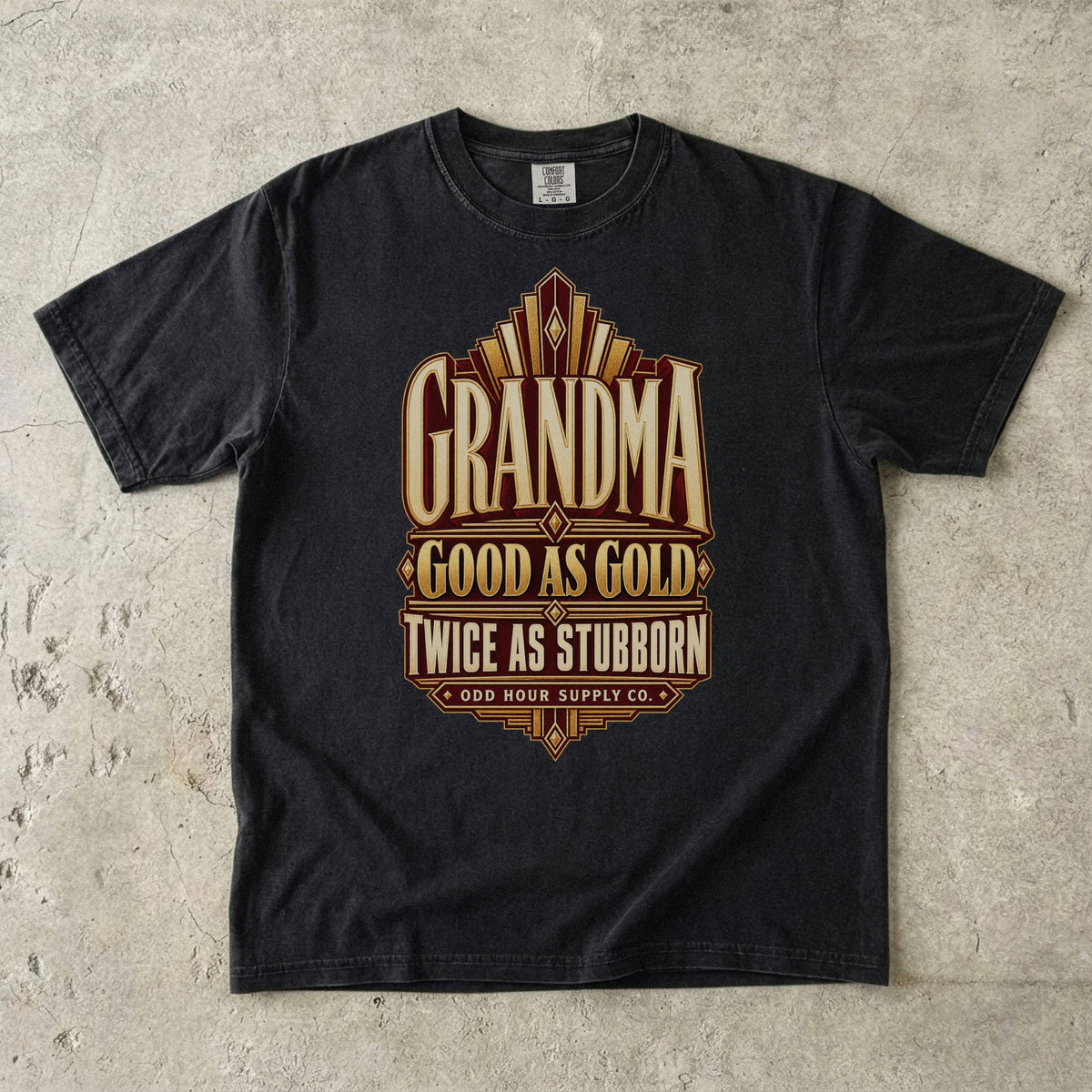Black Comfort Colors 1717 T-shirt with gold geometric lines and Grandma Good as Gold Twice as Stubborn lettering on a burgundy panel.