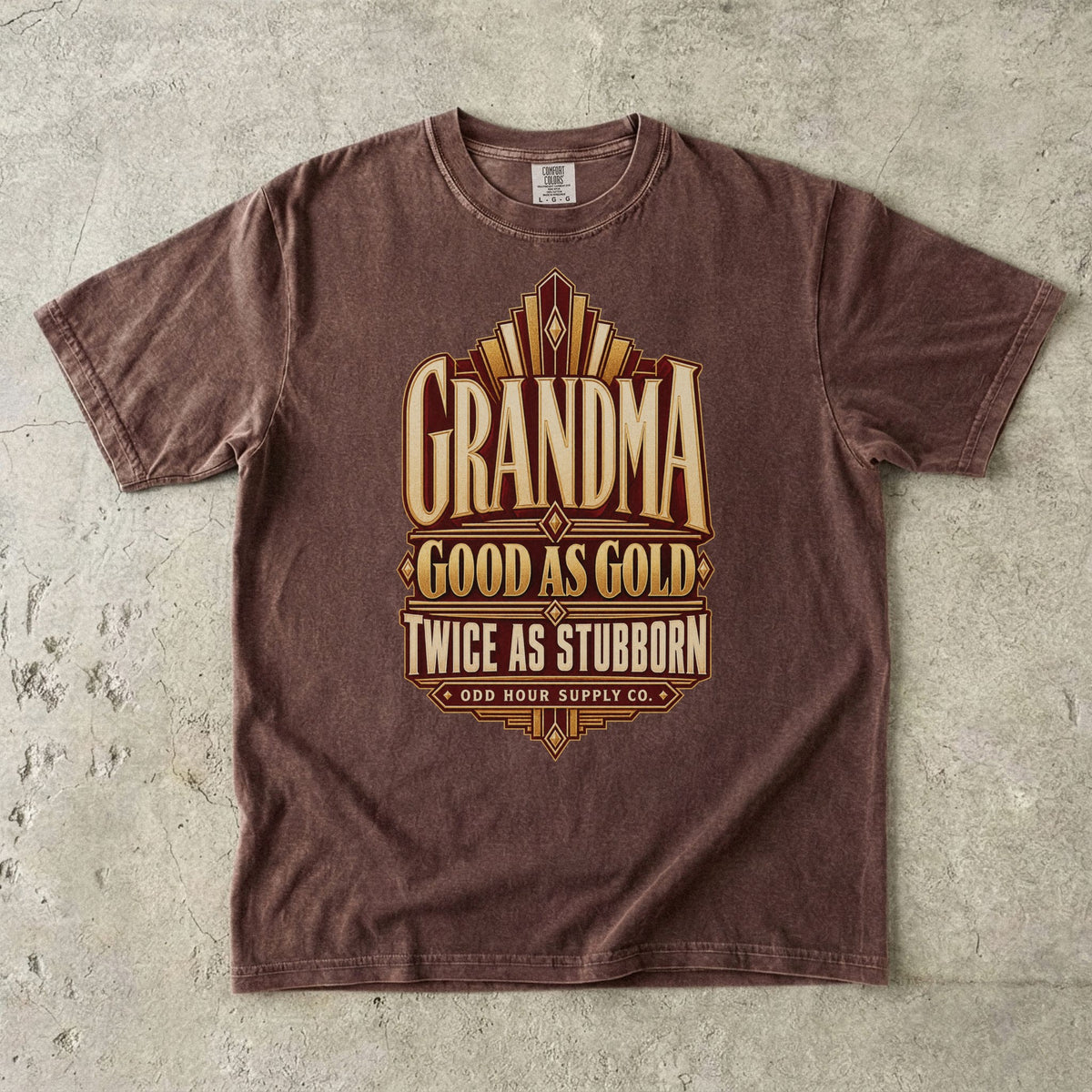 Espresso Comfort Colors 1717 T-shirt with gold geometric lines and Grandma Good as Gold Twice as Stubborn lettering on a burgundy panel.