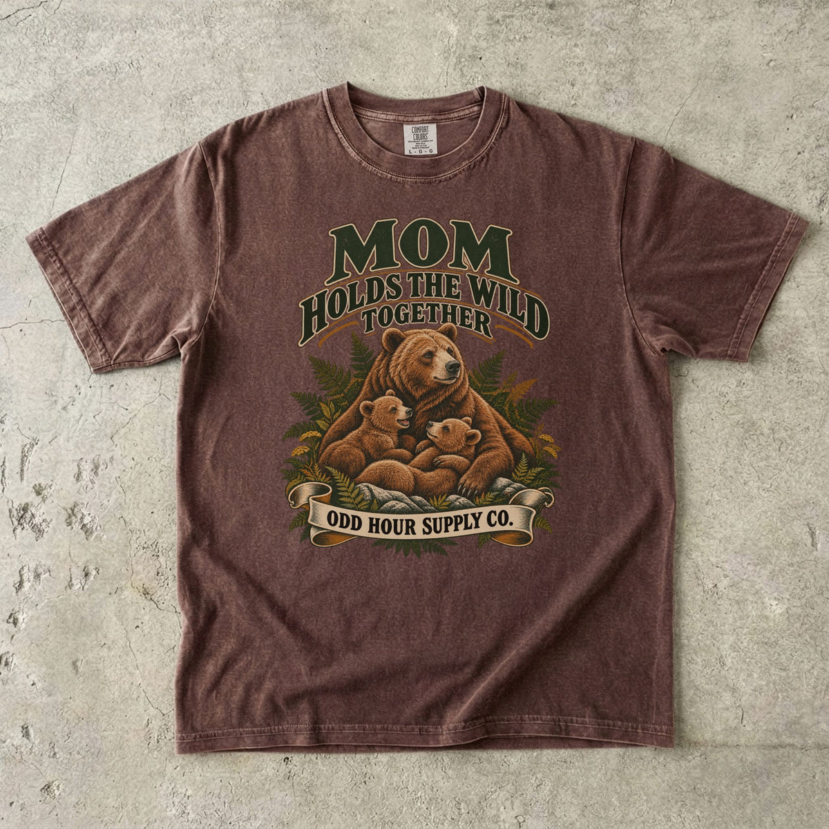 Espresso Comfort Colors 1717 T-shirt with a mother bear, two cubs, ferns, and Mom Holds the Wild Together lettering.