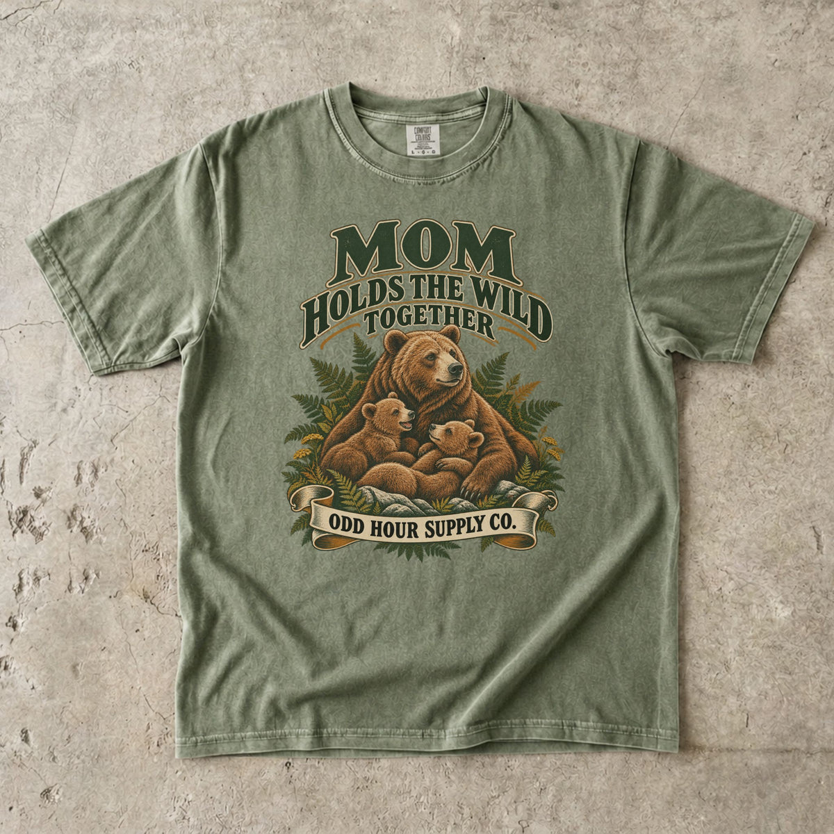 Hemp Comfort Colors 1717 T-shirt with a mother bear, two cubs, ferns, and Mom Holds the Wild Together lettering.