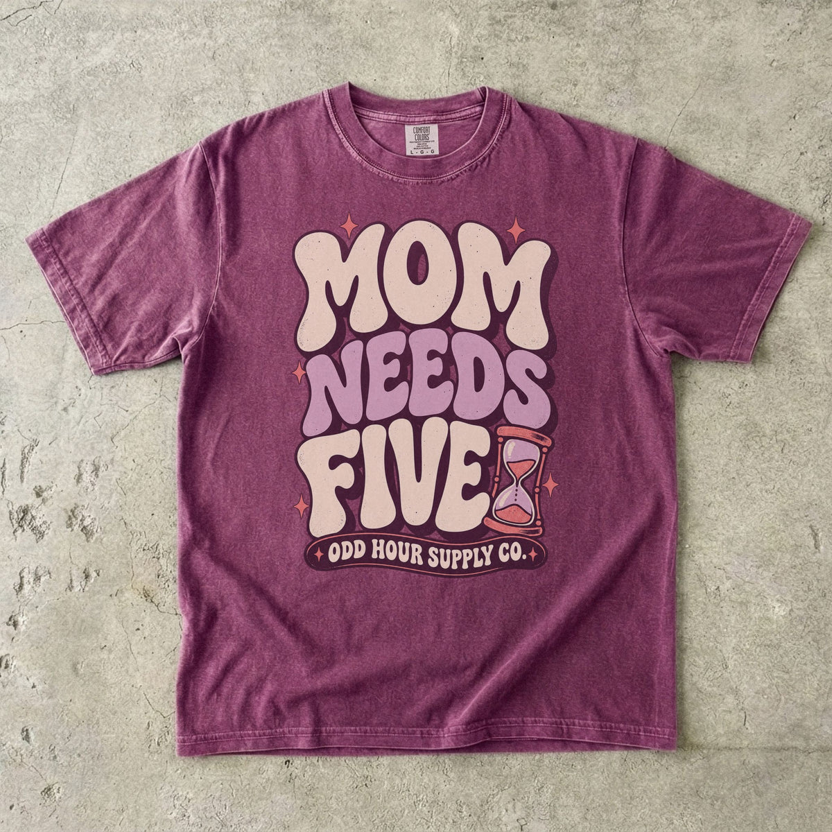 Berry Comfort Colors 1717 T-shirt with cream and lilac Mom Needs Five lettering, pink stars, and an hourglass.