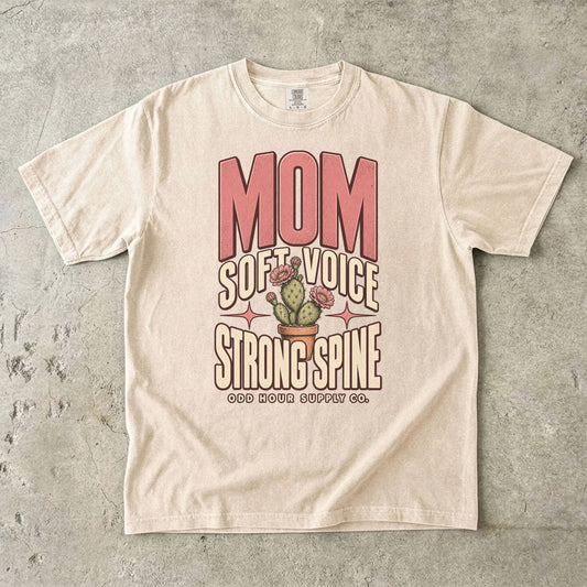 Ivory Comfort Colors 1717 T-shirt with pink Mom lettering, Soft Voice Strong Spine text, and a flowering cactus in a terracotta pot.
