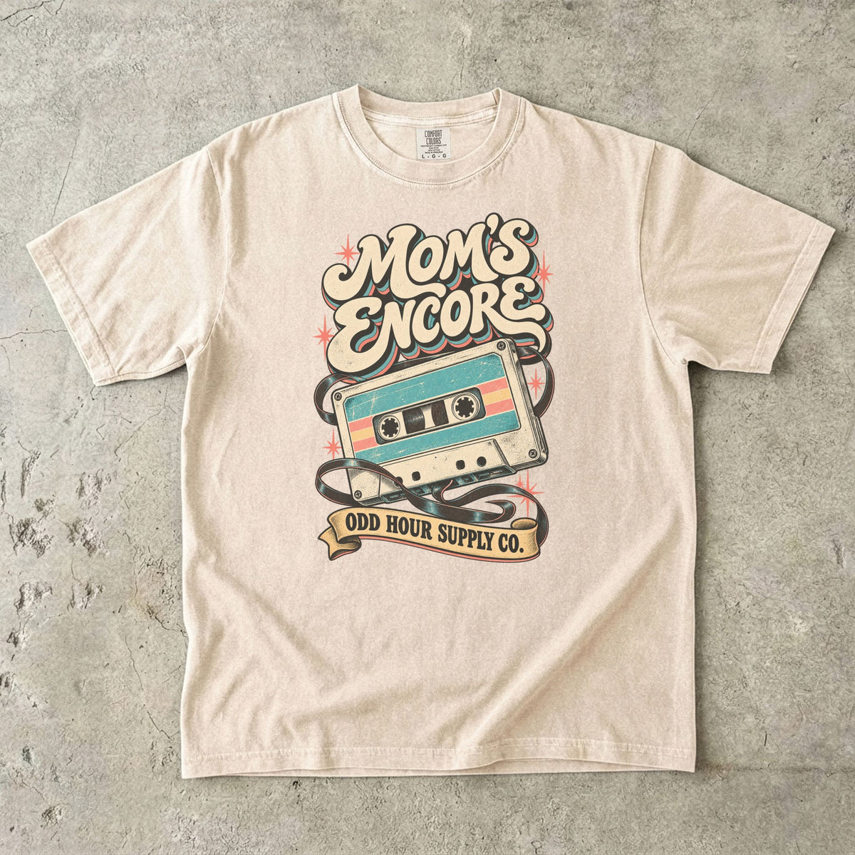 Ivory Comfort Colors 1717 T-shirt with a turquoise and cream cassette, loose tape, coral stars, and Mom’s Encore lettering.