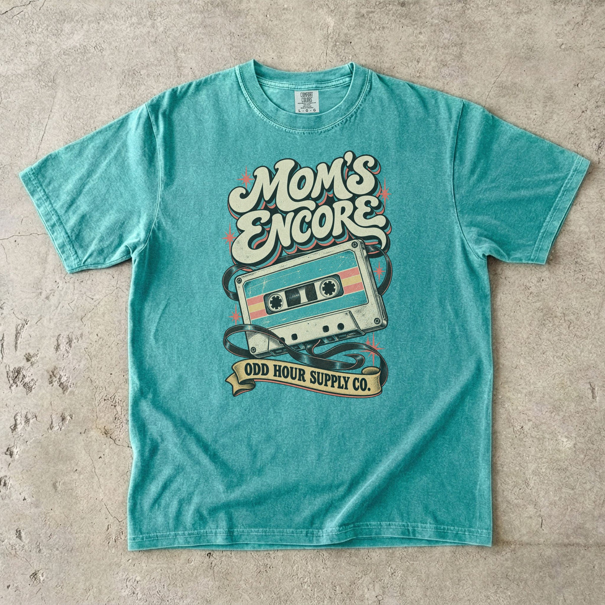 Seafoam Comfort Colors 1717 T-shirt with a turquoise and cream cassette, loose tape, coral stars, and Mom’s Encore lettering.