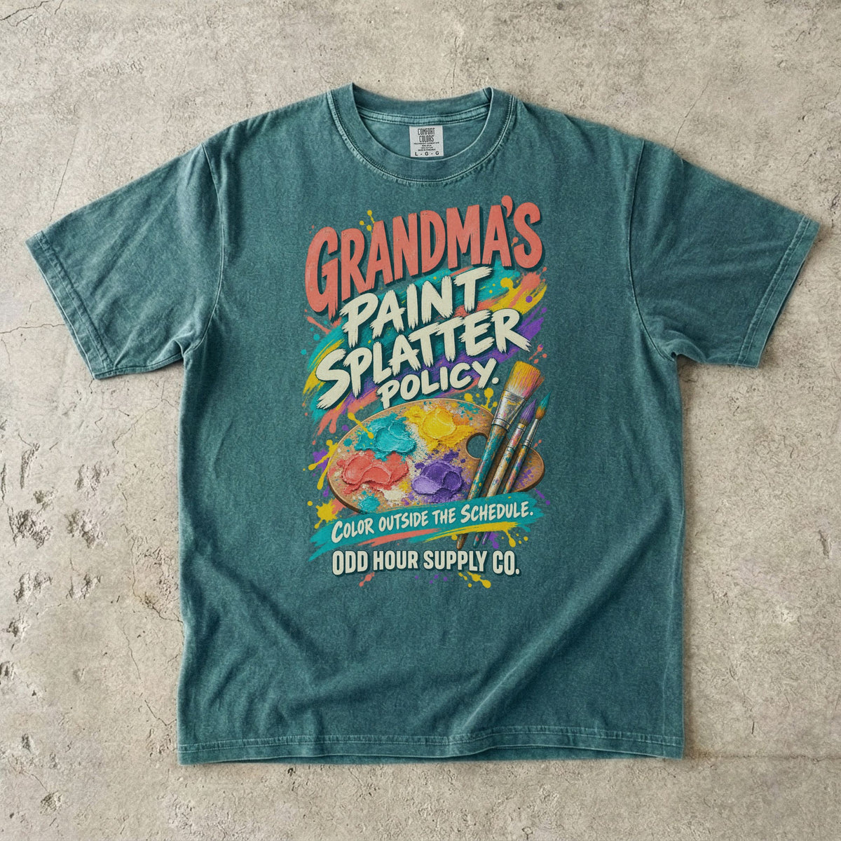 Blue Spruce Comfort Colors 1717 T-shirt with an artist’s palette, paintbrushes, paint splashes, and Grandma’s Paint Splatter Policy and Color Outside the Schedule lettering.