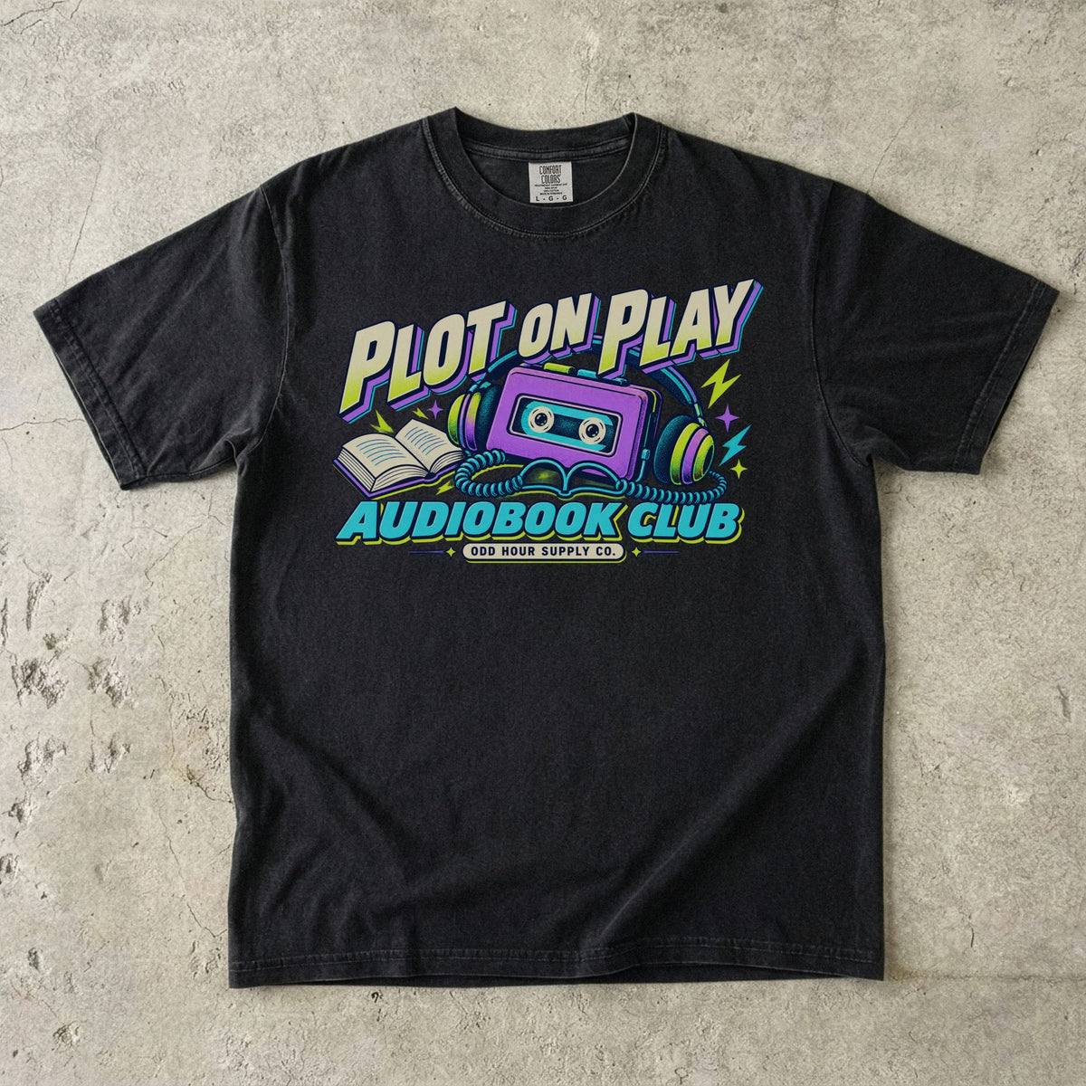 Black T-shirt featuring a purple cassette, headphones and PLOT ON PLAY AUDIOBOOK CLUB by Odd Hour Supply Co.