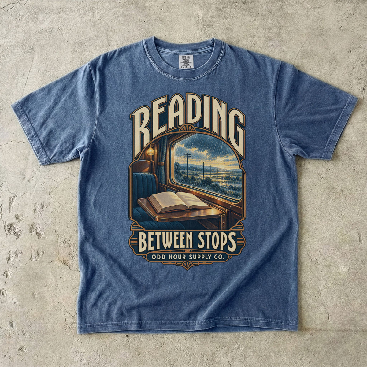 Denim T-shirt with a train window, open book and READING BETWEEN STOPS by Odd Hour Supply Co.