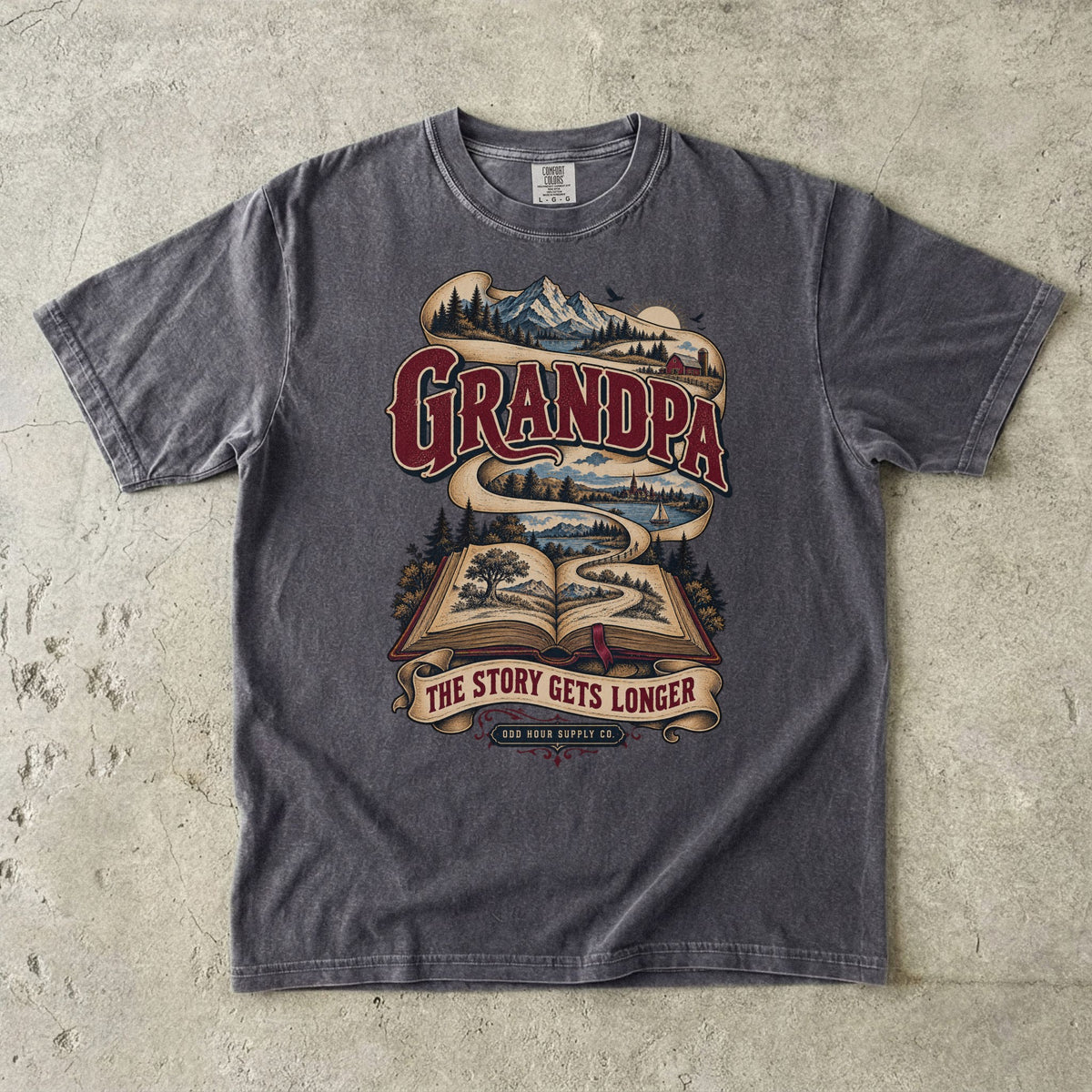 Pepper T-shirt with GRANDPA THE STORY GETS LONGER, an open book and a landscape ribbon by Odd Hour Supply Co.