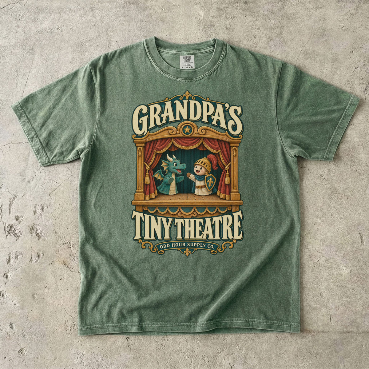 Moss T-shirt with GRANDPA’S TINY THEATRE, a wooden puppet theatre, red curtains, a dragon and a knight by Odd Hour Supply Co.