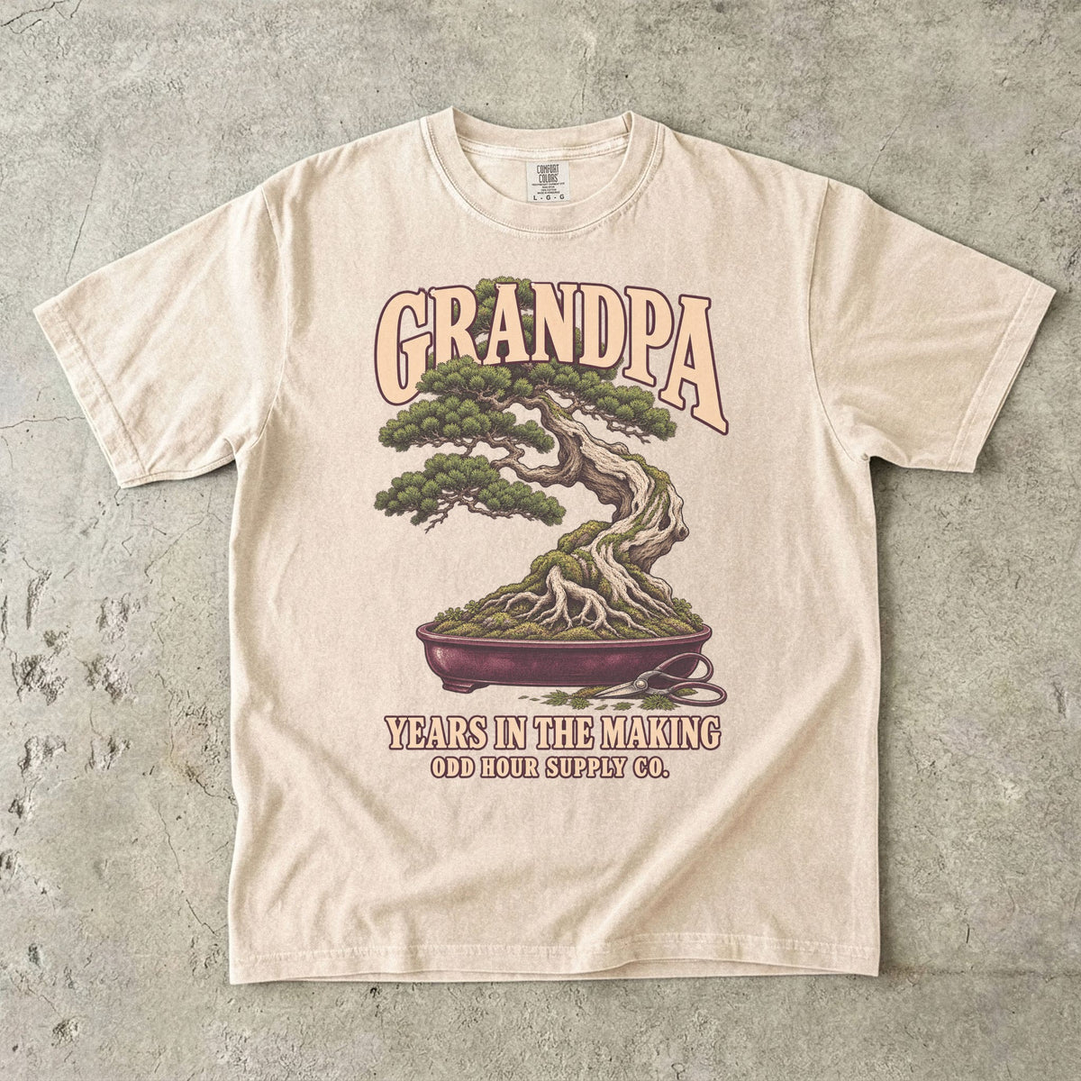 Ivory T-shirt with GRANDPA YEARS IN THE MAKING, a bonsai tree, exposed roots and small pruning shears by Odd Hour Supply Co.